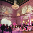 glam - Reinweiss Hochzeiten Elegant event hall with pink lighting, crystal chandeliers, and festively decorated tables.